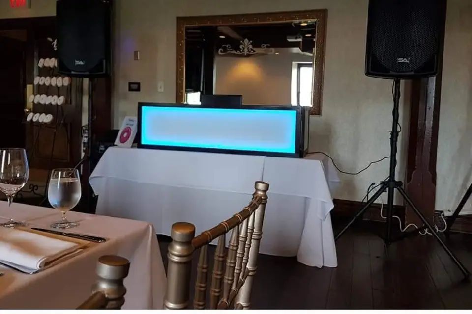 A lit DJ facade and PA speakers set up beside the head table