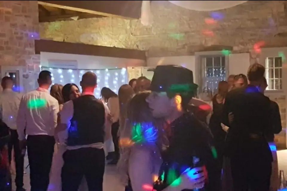 A full dance floor under coloured lights late in a wedding reception